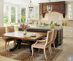 a dining room table and chairs in a large kitchen with white cabinets, leopard print area rug and chandelier hanging from the ceiling