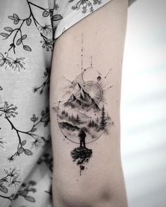 a woman's arm with a tattoo on it that has mountains and trees in the background