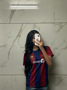 a woman taking a selfie in front of a marble wall with her cell phone