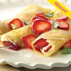 two crepes filled with strawberries on top of a white plate