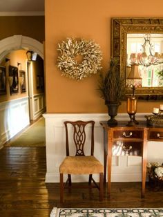 a room with two chairs and a mirror on the wall next to a table that has a wreath on it