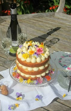 a cake sitting on top of a wooden table next to wine glasses and a bottle