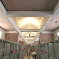 two people walking down a long hallway with lots of caged in areas on both sides