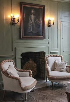 a living room with two chairs and a painting on the wall above it's fireplace