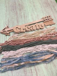 a wooden sign that says create on it next to several different colored yarns and crochet hooks