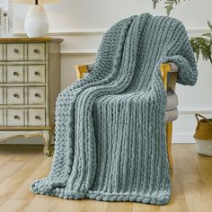 a blue blanket sitting on top of a wooden chair next to a lamp and dresser