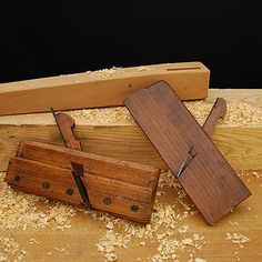 two pieces of wood sitting on top of a wooden cutting board next to a knife