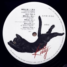 a black cat laying on top of a white disc with red writing and the words kitty