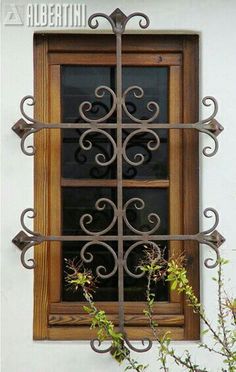 an old window with wrought iron bars on the outside and wood trimmings around it