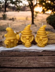 three yellow candles sitting on top of a wooden table