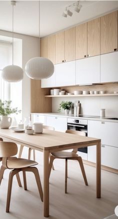 a kitchen with white cabinets and wooden table surrounded by vases on the counter top