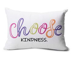 a white pillow with the words choose kindness printed in multicolored letters on it