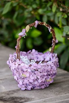 a basket filled with purple flowers sitting on top of a wooden table