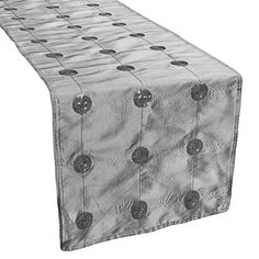 a white table runner with silver circles on the top and bottom, in front of a white background