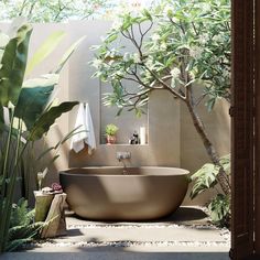 a bath tub sitting in the middle of a bathroom next to a tree and plants