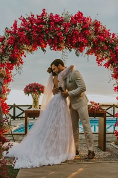 a bride and groom standing under a floral arch