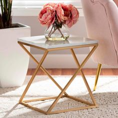 a vase with pink flowers sitting on top of a white table next to a chair