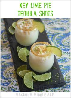 key lime pie tequila shots on a black tray with limes and garnishes