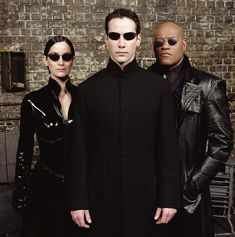 three people standing next to each other in front of a brick wall with sunglasses on