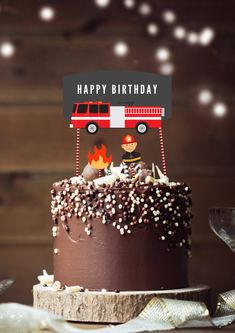 a birthday cake with a firetruck on top and happy birthday sign above it