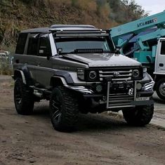 two trucks parked next to each other on a dirt road