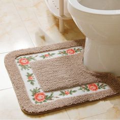 a bathroom rug with flowers on it next to a toilet in the middle of a tiled floor