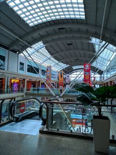 an escalator in a large building with lots of glass and metal roofing