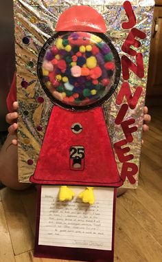 a person holding up a gummy machine made out of paper and some sort of candy