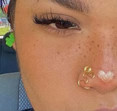 a close up of a person with fake eyelashes and nose piercings on their nose