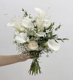 a hand holding a bouquet of white flowers