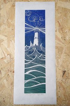 a blue and white print with a lighthouse in the middle of it on a piece of plywood