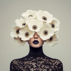 a woman with white flowers on her head and black lace dress, behind which is an image of a mannequin's face