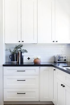 a kitchen with white cabinets and black counter tops