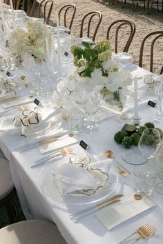 the table is set with white and gold place settings