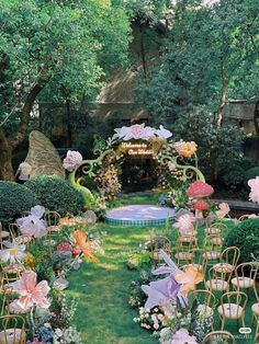 an outdoor ceremony set up with chairs, flowers and umbrellas on the grass in front of