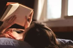 a woman laying in bed reading a book with the words watching her read on it