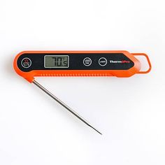 an orange digital thermometer sitting on top of a white table next to a pair of scissors