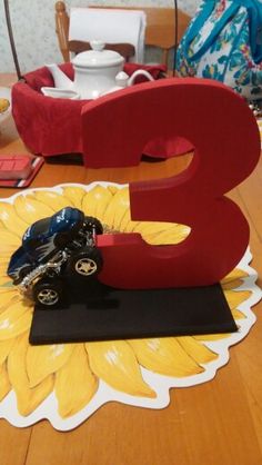 a wooden table topped with a red letter and a toy car