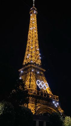 the eiffel tower lit up at night with olympic rings on it's side