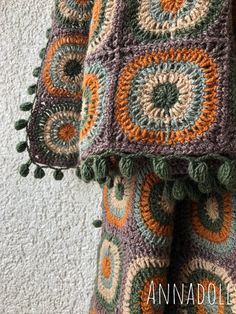 a crocheted blanket with pom poms hanging from it's sides