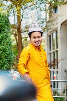 a man wearing a yellow outfit and a silver hat standing in front of a building