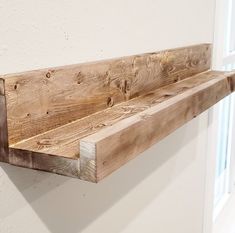 a wooden shelf sitting on top of a white wall