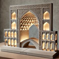 an intricately designed paper sculpture is displayed on a wooden table with lights in the middle