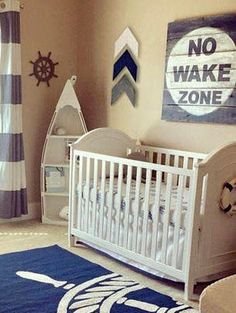 a baby's room decorated in blue, white and gray with nautical decor on the walls