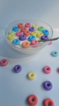 a bowl filled with colorful doughnuts next to a spoon