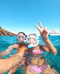 two people in the water with snorkels on their heads making peace signs