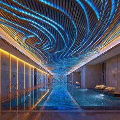 an indoor swimming pool is lit up with blue lights and water features in the ceiling