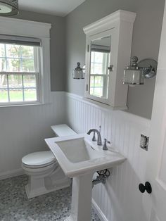 a white bathroom with two sinks and a toilet in the corner next to a window