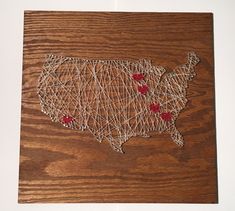 a string art map of the united states on wood with red pins pinned to it