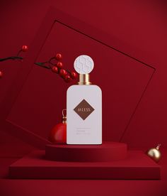 a bottle of cologne sitting on top of a red table next to some ornaments and berries